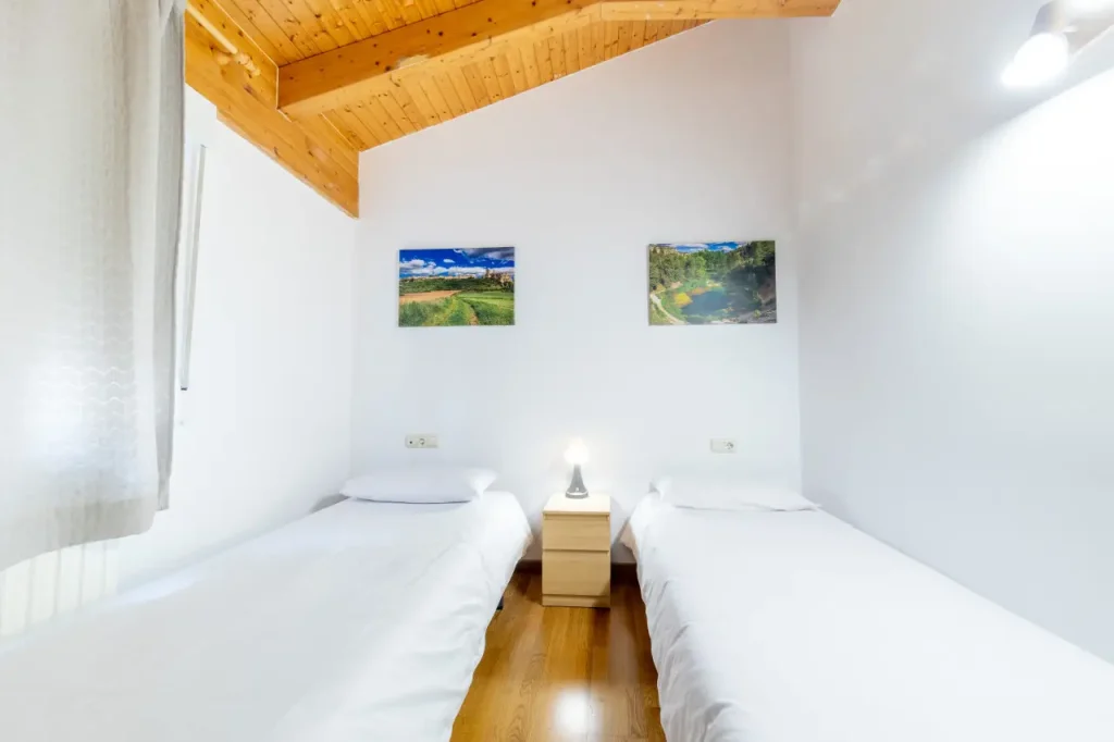 Dormitorio con dos camas individuales y techo abuhardillado de madera