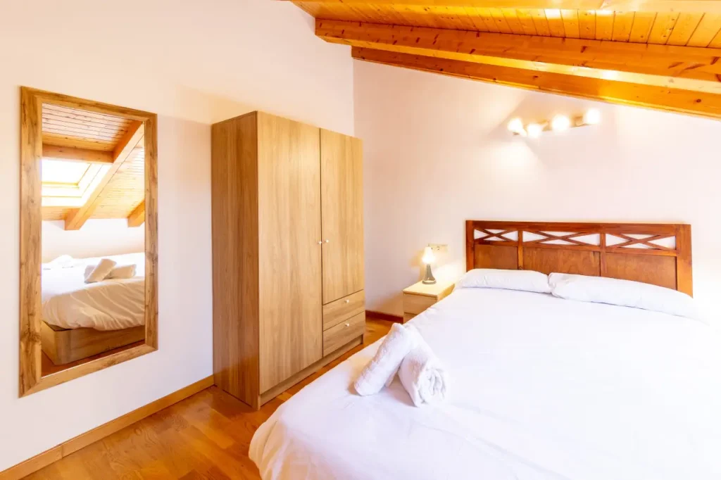 Dormitorio de matrimonio con espejo y armario de madera