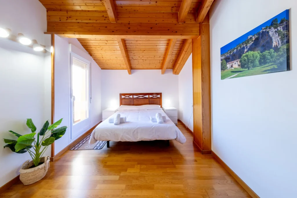 Dormitorio de matrimonio con planta y techo de madera