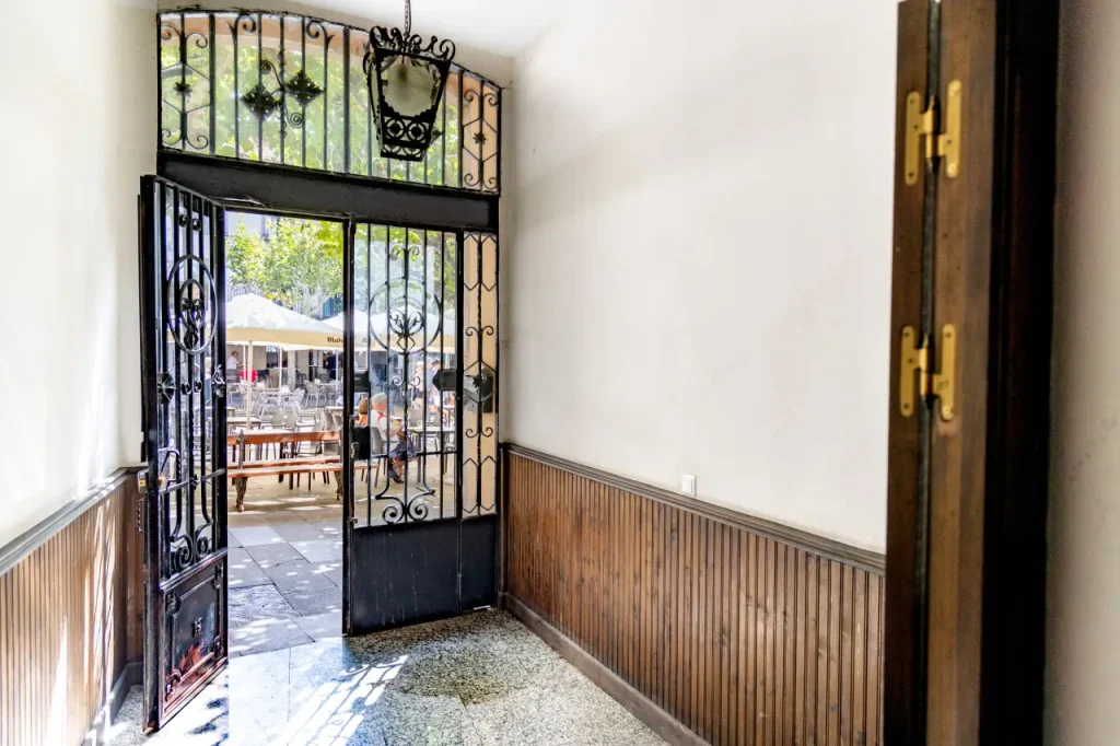 Portal del edificio con cancela de forja abierta a la plaza