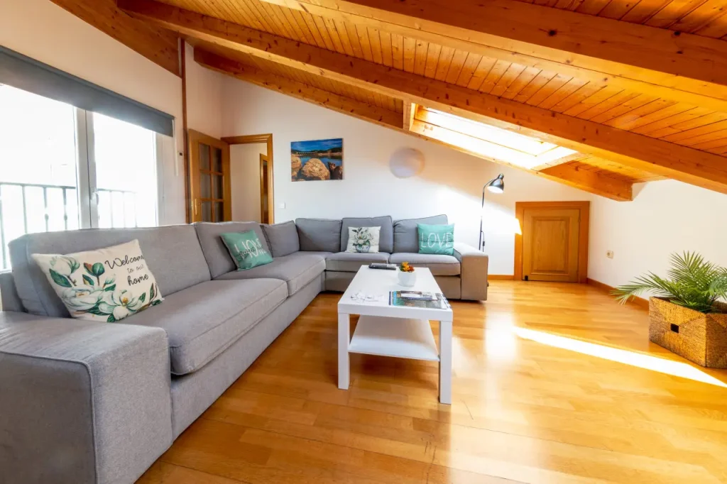 Salón con sofá rinconero, mesa de centro y ventana